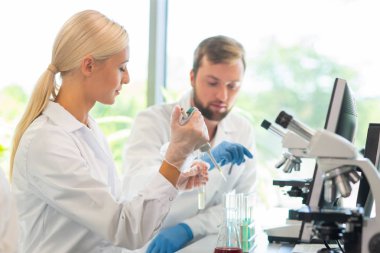 Laboratuvarda çalışan bilim adamları ve öğrenciler. Doktor stajyerlere araştırma yapmayı öğretiyor. Laboratuvar aletleri: mikroskop, test tüpleri, ekipmanlar. Biyoteknoloji, kimya, bakteriyoloji, viroloji, DNA