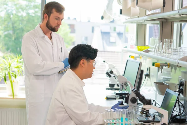 Scientist and students working in lab. Doctor teaching interns to make analyzing research. Laboratory tools: microscope, test tubes, equipment. Biotechnology, chemistry, bacteriology, virology, dna