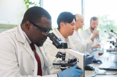 Laboratuvarda çalışan bilim adamları ve öğrenciler. Doktor stajyerlere araştırma yapmayı öğretiyor. Laboratuvar aletleri: mikroskop, test tüpleri, ekipmanlar. Biyoteknoloji, kimya, bakteriyoloji, viroloji, DNA