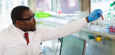 Araştırma laboratuvarında çalışan Afro-Amerikan tıp doktoru. Bilim asistanı ilaç deneyleri yapıyor. Laboratuvar araçları: mikroskop, test tüpleri, ekipman. Kimya, tıp, biyokimya