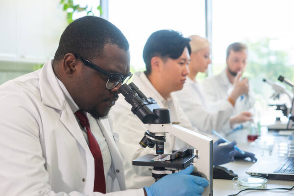 Учёный и студенты работают в лаборатории. Врач учит интернов анализировать исследования. Лабораторные инструменты: микроскоп, пробирки, оборудование. Биотехнологии, химия, бактериология, вирусология, ДНК