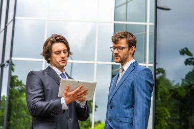 Kendine güvenen iş adamları modern ofis binasının önünde konuşuyorlar. İş adamı ve iş arkadaşı. Bankacılık ve finans piyasası kavramı.