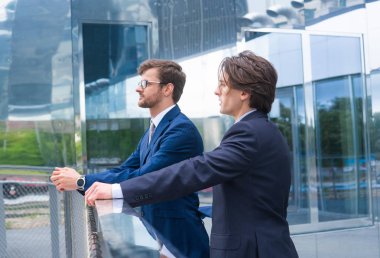 Kendine güvenen iş adamları modern ofis binasının önünde konuşuyorlar. İş adamı ve iş arkadaşı. Bankacılık ve finans piyasası kavramı.