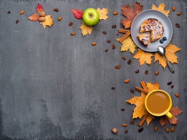 Mevsimlik sonbahar arka planı. Çerçeve renkli akçaağaç yaprakları ve sıcak içecek, kahve, latte veya kapuçino, hindistan cevizi, kek, elma ve tarçın gri üzerinde bir fincan.