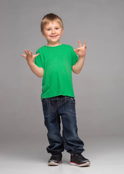 Porträtt av glad leende pojke i grön t-shirt och jeans. Attraktiv grabb i studion. — Stockfoto
