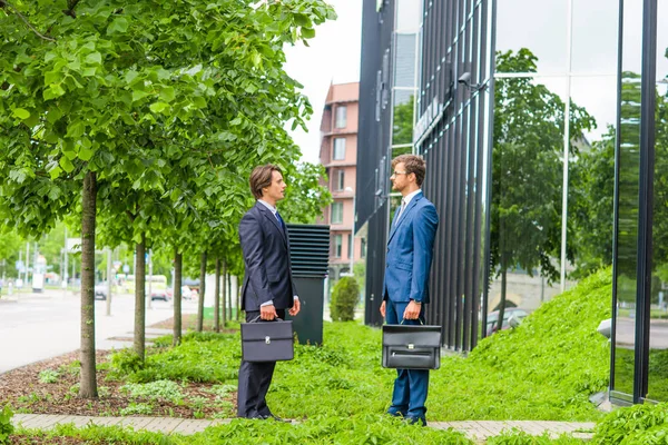 Selbstbewusste Geschäftsleute unterhalten sich vor modernen Bürogebäuden. Geschäftsmann und sein Kollege. Banken- und Finanzmarkt. — Stockfoto