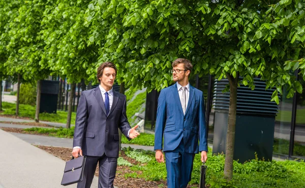 Selbstbewusste Geschäftsleute unterhalten sich vor modernen Bürogebäuden. Geschäftsmann und sein Kollege. Banken- und Finanzmarkt. — Stockfoto