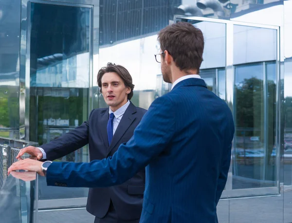 Selbstbewusste Geschäftsleute unterhalten sich vor modernen Bürogebäuden. Geschäftsmann und sein Kollege. Banken- und Finanzmarkt. — Stockfoto