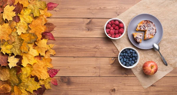 Сезонний осінній фон. Каркас кленового листя і торт і ягоди на дерев'яному фоні . — стокове фото