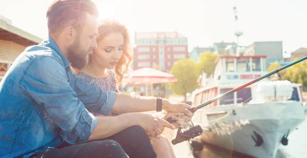 Mann bringt seiner Freundin das Angeln bei. Datum, Liebe und Steckenpferd. Hintergrund Herbst. — Stockfoto