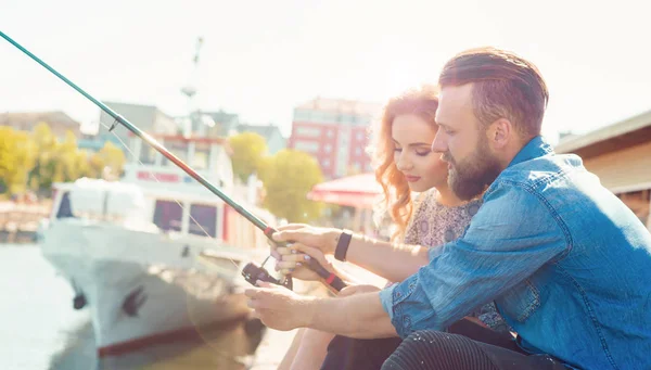Man undervisar sin flickvän för att fiska. Datum, kärlek och hobby koncept. Höst bakgrund. — Stockfoto