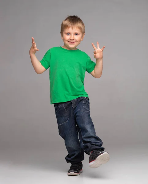 Portrét šťastného usmívajícího se chlapce v zeleném tričku a džínách. Atraktivní kluk ve studiu. — Stock fotografie