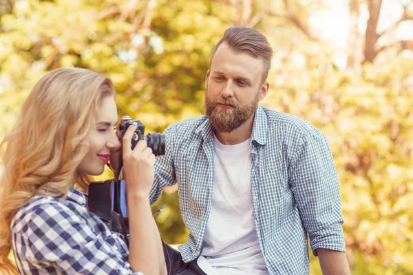 Hombre y mujer teniendo citas al aire libre. Chica ingenio una cámara de fotos y su novio . — Foto de Stock