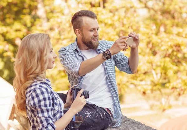 Άνθρωπος και γυναίκα λήψη φωτογραφιών με μια φωτογραφική μηχανή και ένα smartphone στο φθινόπωρο πάρκο. — Φωτογραφία Αρχείου