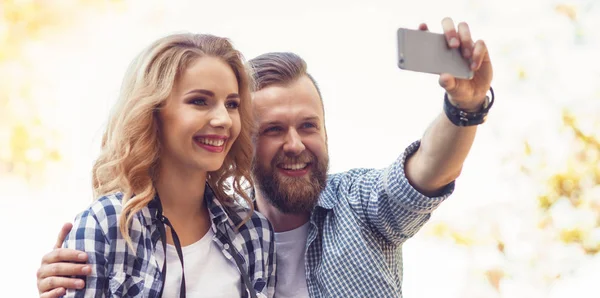 Sonbahar parkında selfie fotoğrafı çeken genç ve sevgi dolu çift.