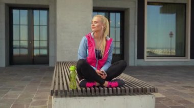 Genç, çekici ve sportif sarışın kız spor müzik dinlerken ve rahatlatıcı açık. Sağlık, spor, fitness ve yaşam tarzı konsepti.