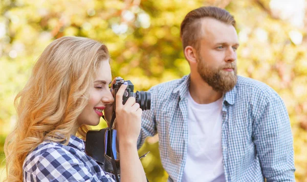 秋に屋外でデートしている男と女 女の子は写真カメラと彼女のボーイフレンドを機知に富んだ 葉の落下の間の公園のカップル 旅のコンセプト — ストック写真