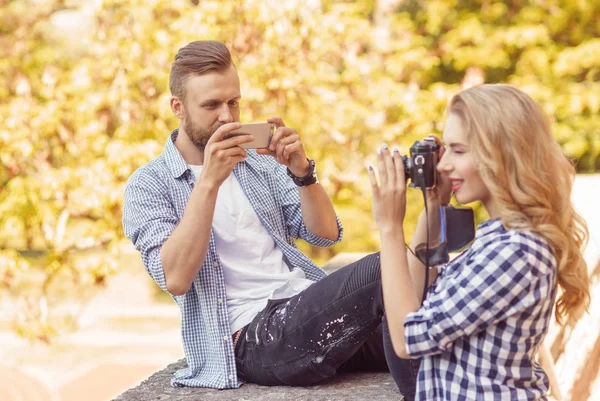 Uomo e donna scattano foto con una fotocamera e uno smartphone nel parco autunnale . — Foto Stock