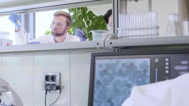 Laboratuvarda çalışan bilim adamları ve öğrenciler. Doktor stajyerlere araştırma yapmayı öğretiyor. Laboratuvar aletleri: mikroskop, test tüpleri, ekipmanlar. Biyoteknoloji, kimya, bakteri, viroloji.