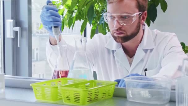 Wetenschapper in het lab. Dokter die microbiologie onderzoek doet. Laboratoriumgereedschappen: microscoop, reageerbuizen, apparatuur. Biotechnologie, chemie, bacteriologie, virologie, DNA en gezondheidszorg. — Stockvideo