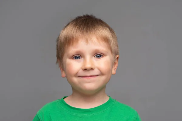 Портрет счастливого улыбающегося мальчика в зеленой футболке. Привлекательный парень в студии. Концепция детства . — стоковое фото
