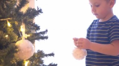 Çekici küçük çocuk Noel ağacını toplar ve ışıklarla süslüyor. Çocuk evde yeni yıla hazırlanıyor..