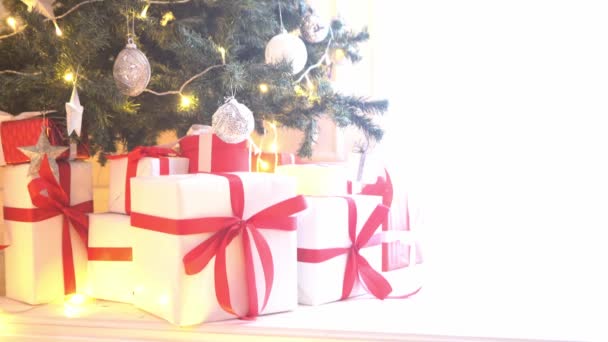 Hermoso árbol de Navidad decorado con bolas y luces. Cajas de regalos, regalos delante . — Vídeo de stock