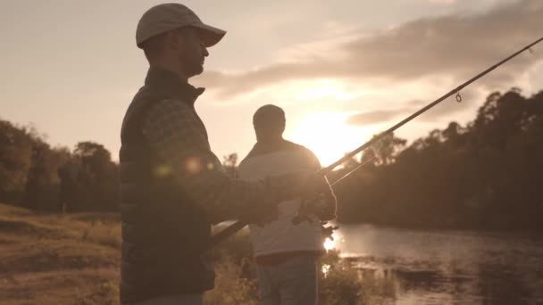 Fischerfreunde mit einer Spinnrute, die auf einem Fluss Fische fängt. Fischermänner an einem Wochenende. Hobby, Freizeit und aktives Sommer- und Herbstkonzept. — Stockvideo