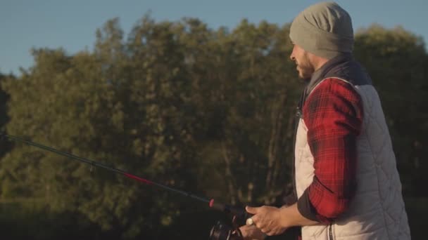 Pescador con una caña giratoria atrapando peces en un río. Fisher un fin de semana. Hobby, ocio y concepto activo de verano y otoño . — Vídeo de stock