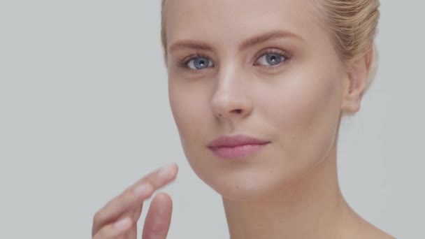 Studio portrait of young, beautiful and natural blond woman applying skin care cream. Face lifting, cosmetics and make-up. — Stock Video
