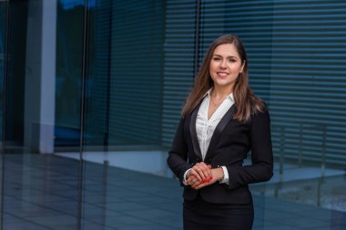 Modern ofis binasının önünde kendine güvenen bir iş kadını. İş, bankacılık, şirket ve finansal piyasa kavramı.