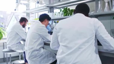 Laboratuvarda çalışan bilim adamları ve öğrenciler. Doktor stajyerlere araştırma yapmayı öğretiyor. Laboratuvar aletleri: mikroskop, test tüpleri, ekipmanlar. Biyoteknoloji, kimya, bakteri, viroloji.