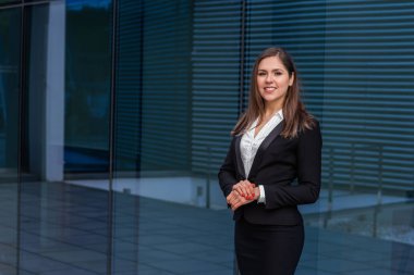 Modern ofis binasının önünde kendine güvenen bir iş kadını. İş, bankacılık, şirket ve finansal piyasa kavramı.