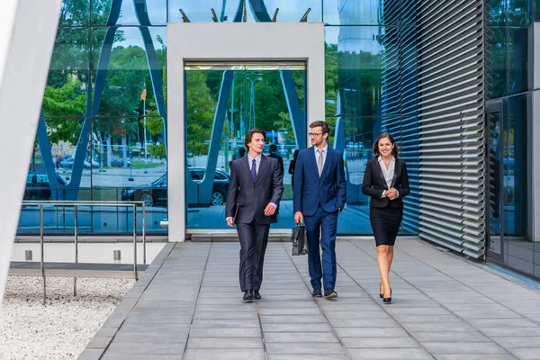 Selbstbewusste Geschäftsleute unterhalten sich vor modernen Bürogebäuden. Geschäftsleute und Geschäftsfrau unterhalten sich. Banken- und Finanzmarktkonzept. — Stockfoto