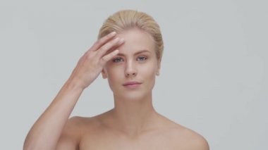 Cilt bakımı kremi süren genç, güzel ve doğal sarışın kadının stüdyo portresi. Yüz gerdirme, makyaj ve makyaj malzemeleri..