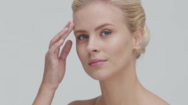 Cilt bakımı kremi süren genç, güzel ve doğal sarışın kadının stüdyo portresi. Yüz gerdirme, makyaj ve makyaj malzemeleri..