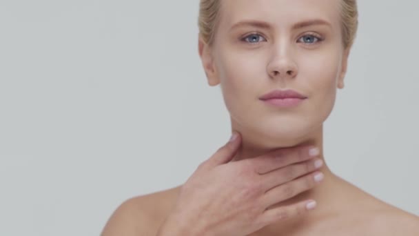 Studioporträt einer jungen, schönen und natürlichen blonden Frau, die Hautpflegecreme aufträgt. Gesichtslifting, Kosmetik und Make-up. — Stockvideo