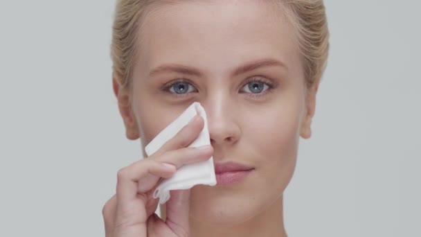 Retrato de estudio de mujer rubia joven, hermosa y natural que aplica crema para el cuidado de la piel. Levantamiento facial, cosméticos y maquillaje . — Vídeo de stock