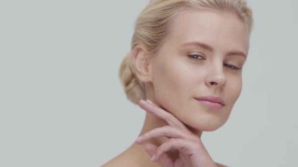 Studio portrét mladé, krásné a přírodní blond ženy, aplikující krém na péči o pleť. Zdvihání obličeje, kosmetika a make-up. — Stock video