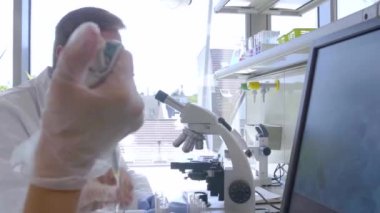 Laboratuvarda çalışan bilim adamları ve öğrenciler. Doktor stajyerlere araştırma yapmayı öğretiyor. Laboratuvar aletleri: mikroskop, test tüpleri, ekipmanlar. Biyoteknoloji, kimya, bakteri, viroloji.