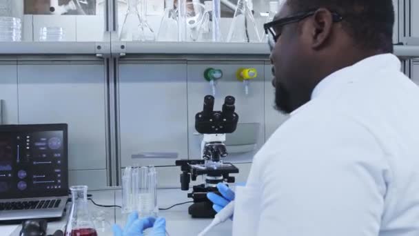 Scientist and students working in lab. Doctor teaching interns to make analyzing research. Laboratory tools: microscope, test tubes, equipment. Biotechnology, chemistry, bacteriology, virology. — Stock Video