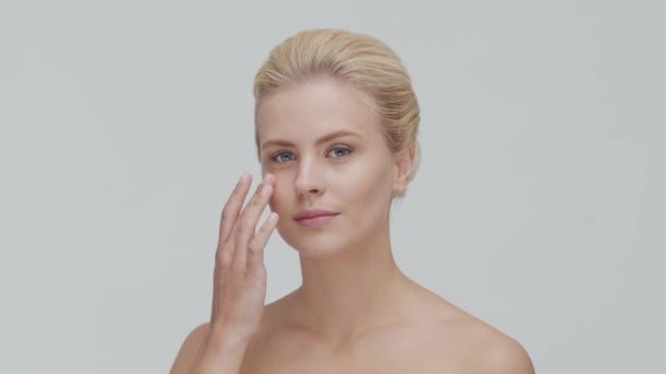 Studio portrait of young, beautiful and natural blond woman applying skin care cream. Face lifting, cosmetics and make-up. — Stock Video
