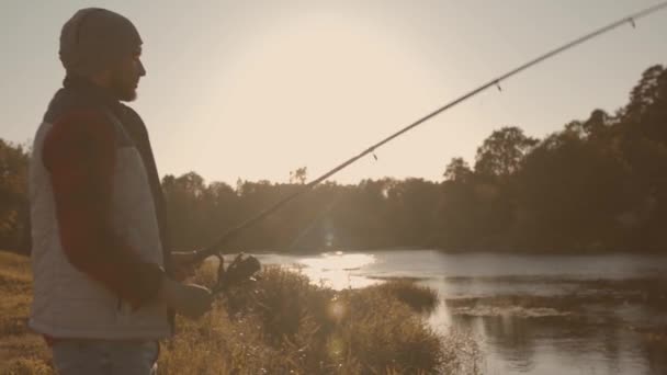 Visser met een draaiende hengel die vis vangt op een rivier. Visser op een weekend. Hobby, vrije tijd en actief zomer- en herfstconcept. — Stockvideo