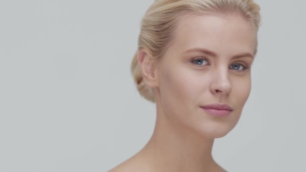 Studio portrét mladé, krásné a přírodní blond ženy, aplikující krém na péči o pleť. Zdvihání obličeje, kosmetika a make-up. — Stock video