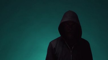 Kapüşonlu bilgisayar korsanı portresi. Karanlık bir yüz. Veri hırsızlığı, internet dolandırıcılığı, darknet ve siber güvenlik .