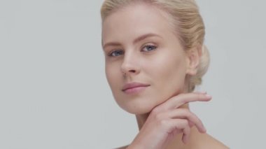 Cilt bakımı kremi süren genç, güzel ve doğal sarışın kadının stüdyo portresi. Yüz gerdirme, makyaj ve makyaj malzemeleri..