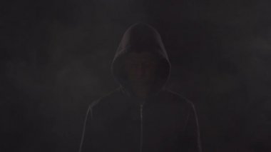 Kapüşonlu bilgisayar korsanı portresi. Karanlık bir yüz. Veri hırsızlığı, internet dolandırıcılığı, darknet ve siber güvenlik .