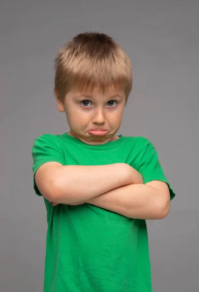 緑のTシャツの少年を怒らせた 灰色の背景でスタジオで悲しいと動揺の子供 幼少期の概念 — ストック写真