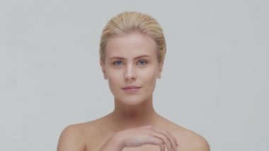 Cilt bakımı kremi süren genç, güzel ve doğal sarışın kadının stüdyo portresi. Yüz gerdirme, makyaj ve makyaj malzemeleri..