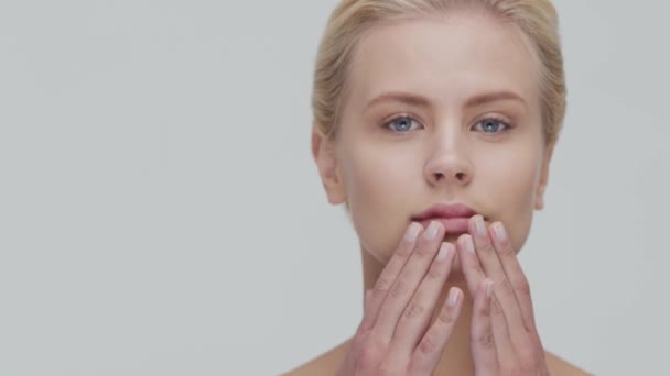 Retrato de estudio de mujer rubia joven, hermosa y natural que aplica crema para el cuidado de la piel. Levantamiento facial, cosméticos y maquillaje . — Vídeo de stock